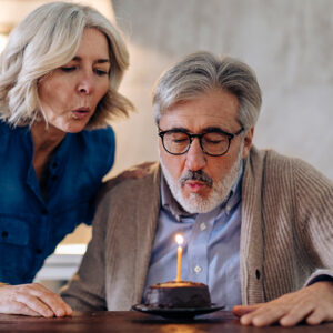 Older man blowing out a birthday candle.