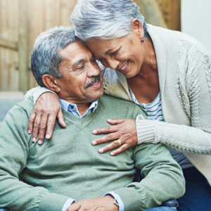 Elderly African American couple embracing each other smiling.