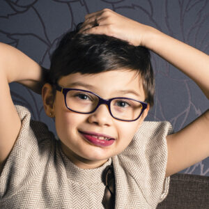 Young boy smiling with hands on head.