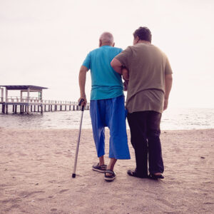 Man assisting an elderly man in walking.
