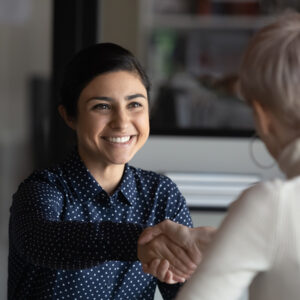 Women shaking hands across a table.