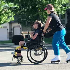 Woman on roller skates pushing a child in a wheelchair.